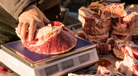 A seller weighs raw uncooked beef meat before wrappingの写真素材
