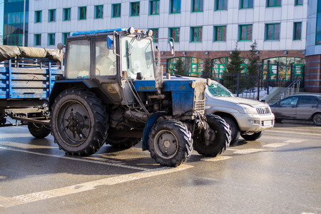 An old blue tractor gets ready to race a modern carの写真素材