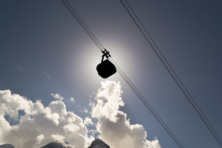 A cable car moves through the sun and a blue skyの写真素材