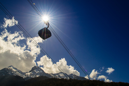 A cable car moves through the sun and a blue skyの写真素材