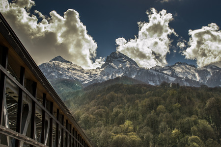 White clouds rise above snow peaked mountain peaks