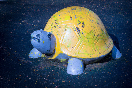 A sad looking yellow concrete tortoise rests on wet asphaltの写真素材