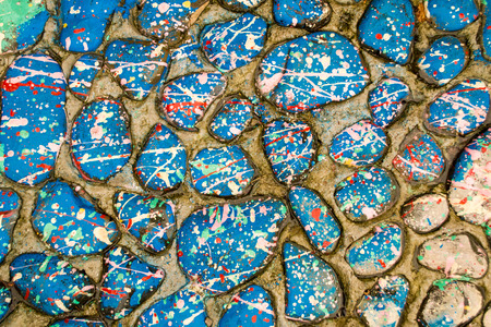 Stones covered in paint drops and drips creating a distinctive splatter patternの写真素材