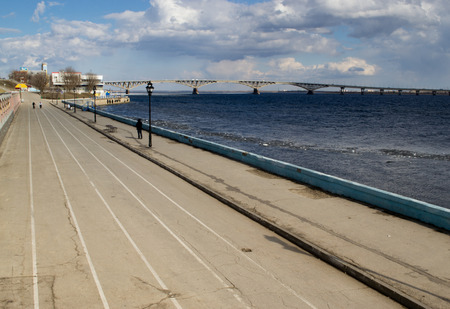 A Bridge reaches over a large river with white clouds in the skyの写真素材