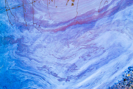 Oil swirls and patterns on the surface of a stagnant pool of waterの写真素材