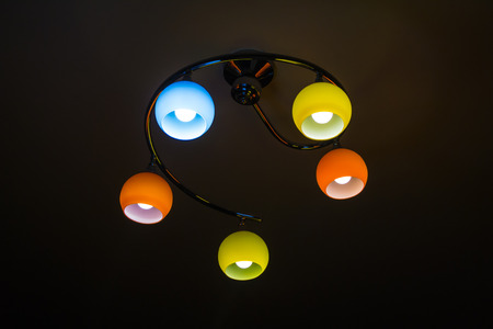 Coloured lamps burning bulbs on a ceiling with reflectionsの写真素材