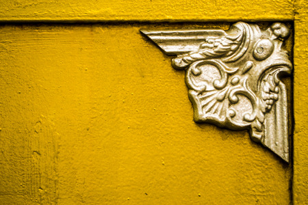 Silver painted emblem marks the corner of edging on a  gold painted surfaceの写真素材