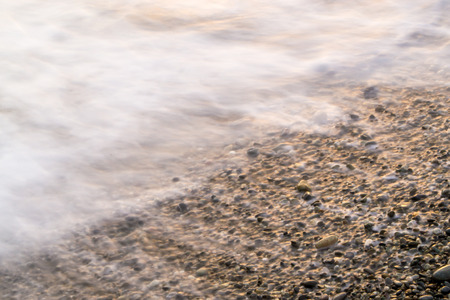 Sea blurs in movement as stones gather the last drops of waterの写真素材