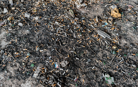 Many waste cigarette butts and dogends on a dusty dirty abandoned concrete floorの写真素材