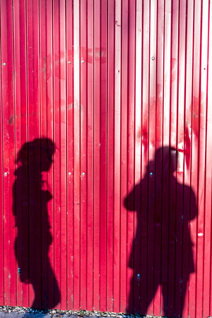 Photographer taking a photo of a woman casting shadows on red metal wallの写真素材