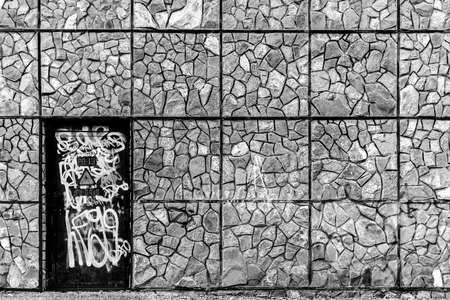 Spray painted black door surrounded by a strong brick wall in black and whiteの写真素材