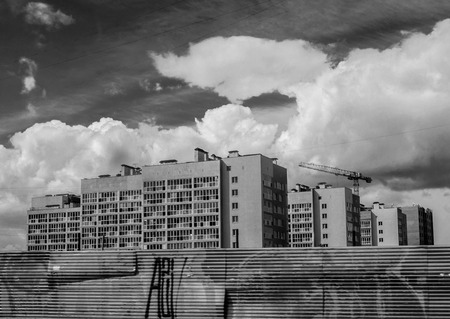 Newly built housing apartments behind a steel fence with a construction craneの写真素材