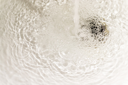 Running bath water and ripples from the water flowの写真素材