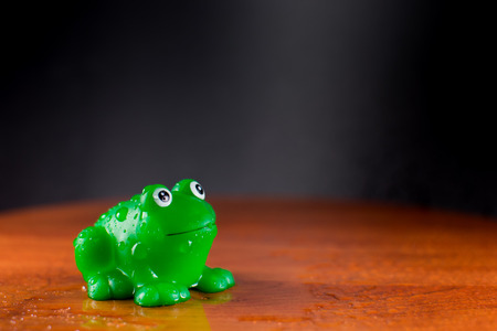 Green plastic frog enjoys a puddle of waterの写真素材