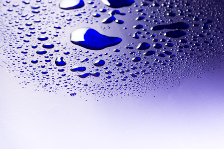 Water droplets reflected from bright blue metal with white copyspaceの写真素材