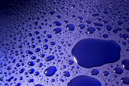 Clear water droplets reflected from bright blue paintの写真素材
