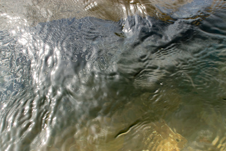 Gently undulating waves from a pool of sea water catching sunlightの写真素材