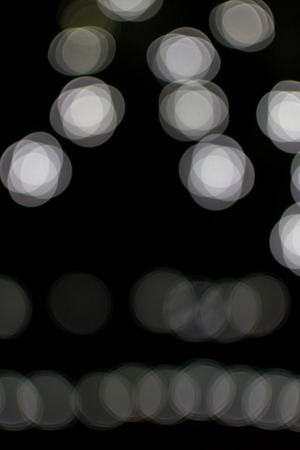 Fading white bokeh blurred light effect using a black backgroundの写真素材