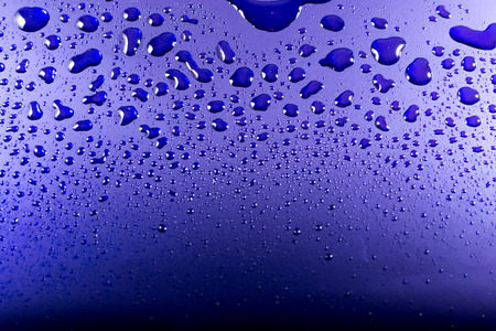 Clear water droplets reflected from bright blue metalの写真素材