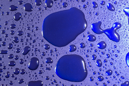Cold water droplets reflected from the surface of turquoise metalの写真素材