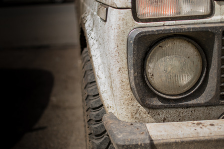 Muddy white jeep covered in dried mud and headlamp with copyspaceの写真素材