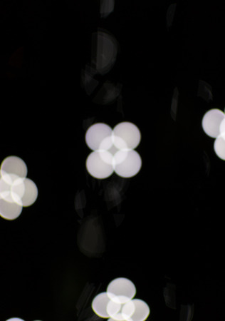 Flower shaped white bokeh blurred light effect using a black backgroundの写真素材