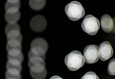 Fading white bokeh blurred light effect using a black backgroundの写真素材