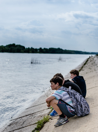 Three school children in casual clothing relaxing by the river in Ufa May 2015のeditorial素材