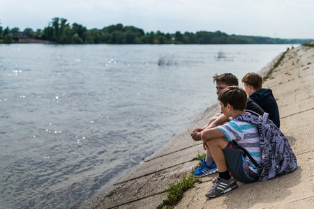 Three school children in casual clothing relaxing by the river in Ufa May 2015のeditorial素材