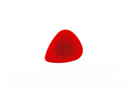 Single red guitar plectrum with no insignia on a white backgroundの写真素材