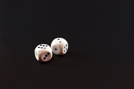 Two white casino plastic dices on a black backgroundの写真素材