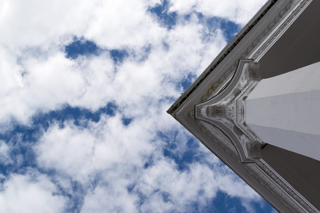 White marble style Greek Roman column against a blue sky and clouds