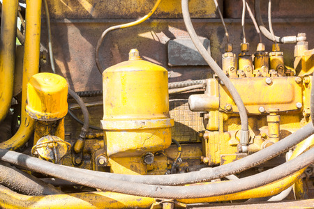 Close-up of an oill stained engine compartment of a yellow industrial earth excavator machine in monochromeの写真素材