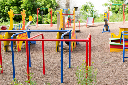 Modern playground with brightly colored metal slides swings seesaws and playbars