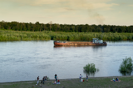 Large ferry sailing on a river as people relax on the riverbank in Ufa Russian in July 2015の写真素材