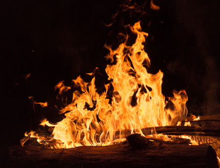 Closeup of bright golden color flames from a campfire at nightの写真素材