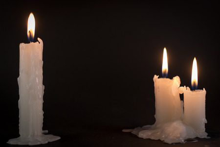 Three white candles burning during the darkness of night timeの写真素材