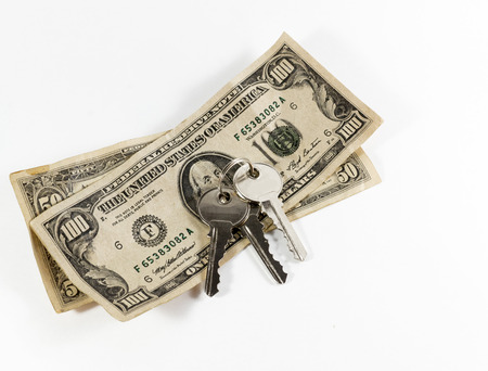House keys with US hundred dollar bill on a white backgroundの写真素材