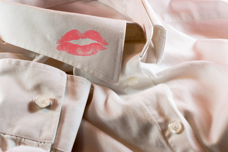 Close-up of a man's white business shirt with a smudge of a woman's bright red lipstick on the collarの写真素材