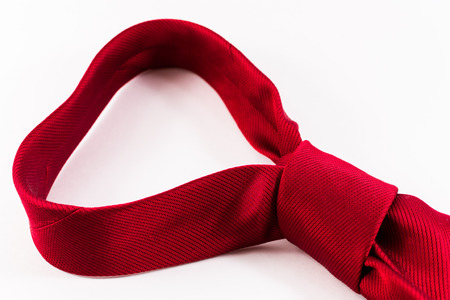 Single knotted red woven silk tie belonging to a modern business man on a white backgroundの写真素材