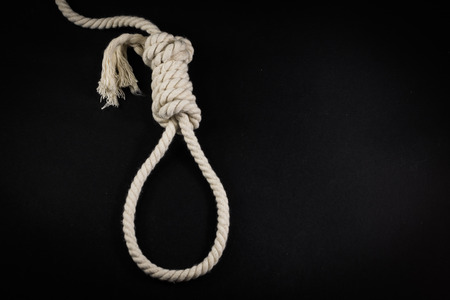 Empty Hangman's noose made from white rope set against a black studio backgroundの写真素材
