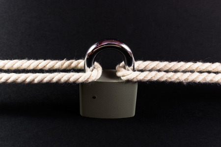 Locked padlock secures two separate ropes togetherの写真素材
