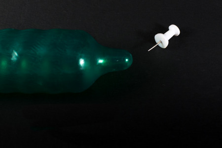 Metal pin threatens to pierce a rubber latex condom and reduce protectionの写真素材