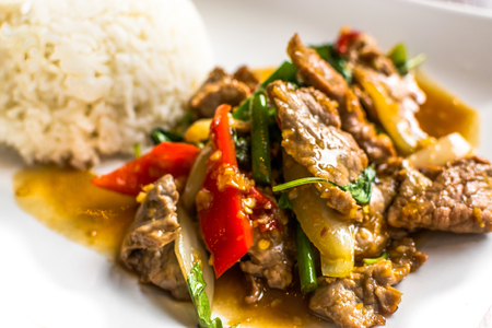 Freshly cooked Thai Fried Basil Dish on  a white plate with white rice untouched and ready to be eaten with nobody presentの写真素材