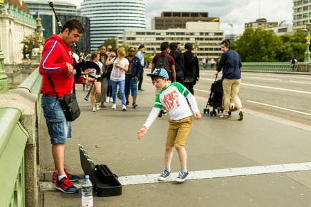 18th of August - Busker plays the Westminster bridge near big ben as a happy caring child throws coins into his caseのeditorial素材