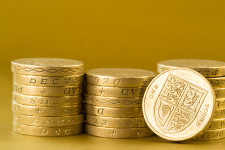 Three piles of English pound coins set against a golden backgroundの写真素材