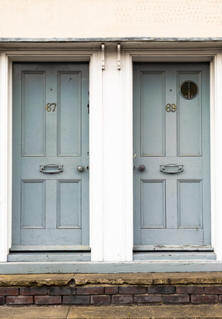 Pair of grey painted wooden residential front doors set in a white wall exteriorの写真素材