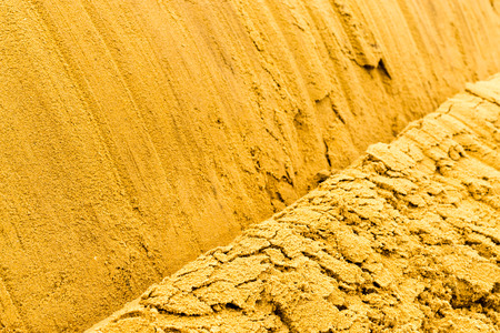 Closeup of freshly poured yellow sand with a single crest