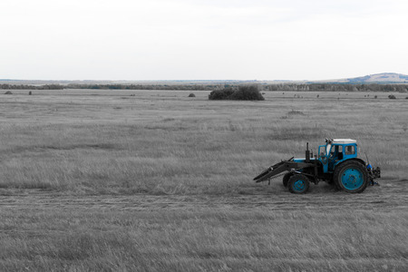 Old blue tractor in a large field stands stationaryの写真素材