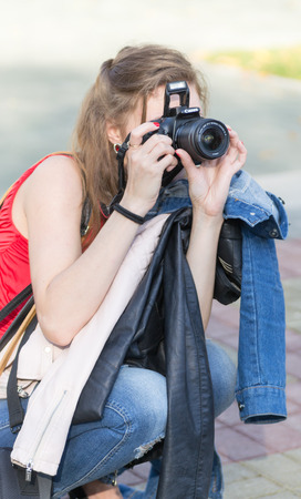 23/09 - Young woman tourist in casual clothes kneels down to take a photograph in Ufa Russia during the autumn of 2015のeditorial素材
